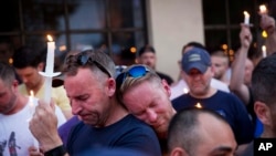 Paul Cox, right, leans on the shoulder of Brian Sullivan, as they observe a moment of silence during a vigil for a fatal shooting at an Orlando nightclub, June 12, 2016, in Atlanta.