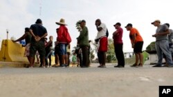 FILE - Migrants seeking asylum in the United States line up for a meal provided by volunteers near the international bridge in Matamoros, Mexico, April 30, 2019. 