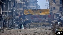 Syrian pro-government forces walk in Aleppo's Bustan al-Qasr neighborhood after they captured the area in the eastern part of the war torn city, Dec. 13, 2016.