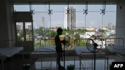 A worker places fans by beds in a stadium, which has been converted into a quarantine center for Covid-19 coronavirus patients in Kolkata on April 21, 2021.