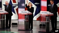 Hillary Clinton waves as Bernie Sanders, left, and Martin O'Malley prepare before a Democratic presidential primary debate, Nov. 14, 2015, in Des Moines, Iowa.