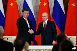 រូបឯកសារ៖ ប្រធានាធិបតីចិន លោក Xi Jinping និងប្រធានាធិបតីរុស្ស៊ី លោក Vladimir Putin ចាប់ដៃស្វាគមន៍គ្នានៅក្នុងសន្និសីទសារព័ត៌មានមួយ នៅវិមានក្រឹមឡាំង ក្នុងទីក្រុងមូស្គូ ប្រទេសរុស្ស៊ី កាលពីថ្ងៃទី ២១ ខែមីនា ឆ្នាំ ២០២៣។ (Mikhail Tereshchenko, Sputnik, Kremlin Pool Photo via AP, File)