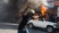 A protester runs past a burning car during a protest against President Michel Martelly's government in Port-au-Prince, Haiti, Jan. 18, 2016.