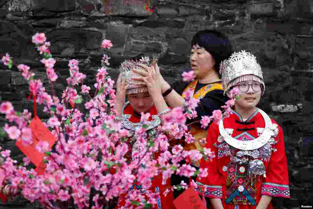 A teacher adjusts the crown of a Hill Street student dressed in the traditional clothing of the Miao ethnic group of China to welcome the Lunar New Year community celebration of the year of the snake, in Dublin, Ireland.