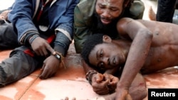 Des migrants africains se reposent à même le sol après avoir traversé une clôture frontalière entre le Maroc et l'enclave espagnole de Ceuta, en Afrique du Nord, le 31 octobre 2016. 