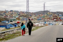 FILE - Residents walk in the town of Aasiaat, Greenland, on June 29, 2024.