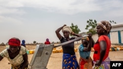 FILE - Women fetch water at the Minawao refugee camp near Gadala, Cameroon, March 3, 2020.