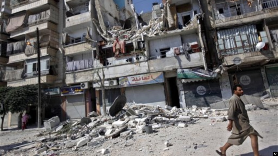 Cư dân đi ngang qua một tòa nhà bị phá hủy trong các vụ không kích ở Aleppo, Syria.