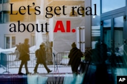 FILE - People reflected in a window of a hotel at the Davos Promenade with a slogan about AI alongside the World Economic Forum in Davos, Switzerland, January 15, 2024