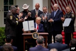 President Donald Trump holds up an executive order on police reform after signing it in the Rose Garden of the White House, in Washington, June 16, 2020.
