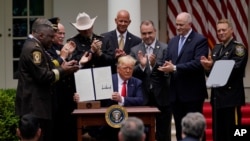 President Donald Trump holds up an executive order on police reform after signing it in the Rose Garden of the White House, in Washington, June 16, 2020.