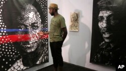 Artist Roger Karera explains portraits works, by Togolese artist Koffi Mens, of Ghana's first president, Kwame Nkrumah (L) and Burkina Faso's assassinated leader Thomas Sankara (R) during the African Culture and Design Festival in Lagos, Nigeria, Nov. 10,