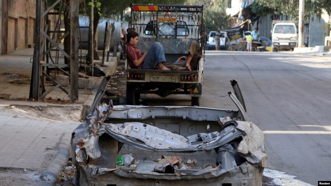 Men rest at the back of a pickup truck near a damaged car in the rebel held al-Katerji district in Aleppo, Syria, Aug. 13, 2016. 
