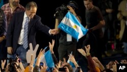 Ruling party presidential candidate Daniel Scioli holds an Argentine flag as he acknowledges supporters after primary elections in Buenos Aires, Argentina, Aug. 10, 2015.