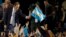 FILE - Ruling party presidential candidate Daniel Scioli holds an Argentine flag as he acknowledges supporters after primary elections in Buenos Aires, Argentina, Aug. 10, 2015.