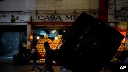 ARCHIVO - Un porteador traslada cajas de mercadería en la Central de Abastos, el mercado más grande y más completo de alimentos y bienes, en Ciudad de México, en agosto de 2022. 