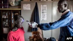 Prise de température d'un garçon dans un refuge pour enfants de rue nouvellement arrivés, à l'extérieur de Dakar, le 10 avril 2020.