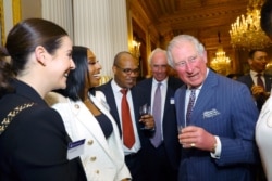FILE - Prince Charles speaks with Alexandra Burke and other guests during the Commonwealth Reception at Marlborough House, in London, March 9, 2020.