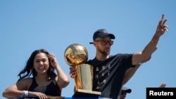  Stephen Curry et Ayesha Curry saluent la foule, lors du défilé organisé pour les nouveaux champions NBA, le 15 juin 017, Oakland, Californie. (Kyle Terada-USA TODAY Sports)