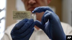 FILE - A researcher holds a vial of an experimental Ebola vaccine in Oxford, England, Sept. 17, 2014.