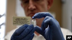 FILE - A researcher holds a vial of an experimental Ebola vaccine in Oxford, England, Sept. 17, 2014.