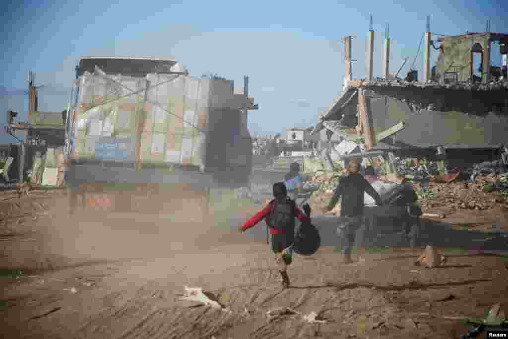 Palestinians run towards aid trucks, following a ceasefire between Israel and Hamas, in Rafah in the southern Gaza Strip.