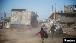 FILE - Palestinians run towards aid trucks, following a ceasefire between Israel and Hamas, in Rafah in the southern Gaza Strip, Jan. 20, 2025.