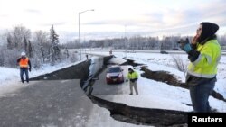 Sebuah mobil terjebak di jalanan yang hancur akibat gempa di kota Anchorage, Alaska, Jumat (30/11).