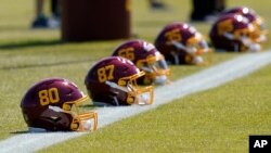 File-This May 14, 2021, file photo shows helmets for the Washington Football Team placed on the sideline during an NFL football rookie minicamp at Inova Sports Performance Center in Ashburn, Va. 
