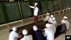 Seorang guru menjelaskan ayat-ayat Al-Qur'an yang dicetak pada pelat logam di kelas baca Al-Qur'an selama bulan Ramadhan di Pondok Pesantren Al-Ashriyyah Nurul Iman, Parung, Jawa Barat, Selasa, 6 Juni 2017. (Foto: dok).