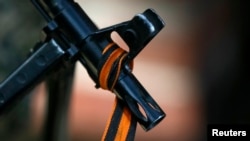 FILE - The black and orange ribbon of St. George, a symbol widely associated with pro-Russian protests in Ukraine, is tied to the machine gun of a pro-Russian armed man in Slaviansk, Kazakhstan, April 21, 2014. 