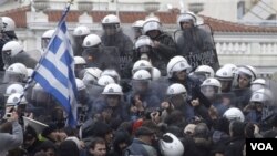 Polisi anti huru-hara menghalang-halangi demonstran yang berusaha masuk ke gedung Parlemen Yunani di Athena (7/2).