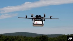 FILE - A prototype drone is seen carrying a parcel for delivery.