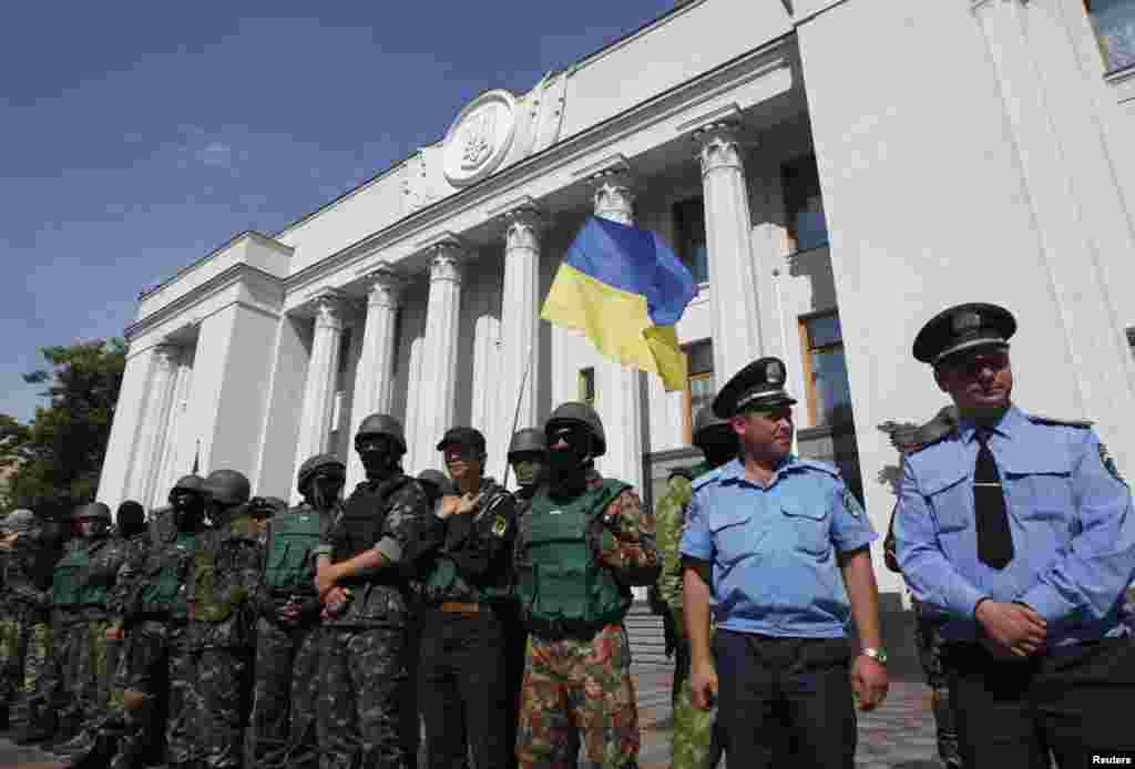 Volunteers from the Donbass battalion and Maidan self-defense group stand guard with official security guards outside the Ukrainian parliament in Kyiv, July 3, 2014. 