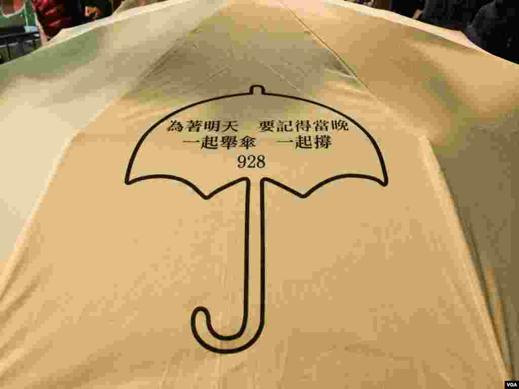 有香港市民撑着印有雨伞运动标志的黄色雨伞，参加平安夜游行