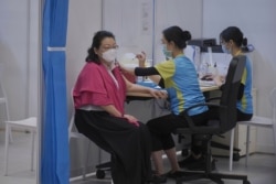 Hong Kong Secretary for Justice Teresa Cheng, left, receives the second dose of the Sinovac Biotech COVID-19 vaccine at Central government office in Hong Kong, March 22, 2021.