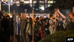 Israelis look on as a Israeli helicopter with released hostages prepares to land at Tel Aviv's Schneider medical centre on November 24, 2023. 