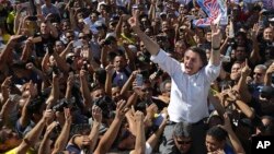 National Social Liberal Party presidential candidate Jair Bolsonaro greets supporters as he gets a shoulder ride from a member of his security detail, in Brasilia's Ceilandia neighborhood, Sept. 5, 2018.