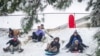 Sledders ride down a hill as snow falls in Florence, Alabama, Jan. 10, 2025.