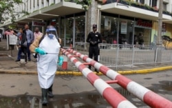 A worker sprays disinfectant on a security barrier outside a hotel to prevent the spread of coronavirus disease along the streets in downtown Nairobi, Kenya, March 19, 2020.