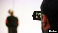 FILE - A police cameraman takes video footage of the hanging of a convicted murderer at Jamshidieh park in Tehran, Oct. 27, 2002.