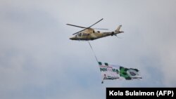  Un hélicoptère de l'armée de l'air nigériane fait voler une bannière lors de la célébration du 60e anniversaire de l'indépendance du pays, le 1er octobre 2020, à Abuja. 