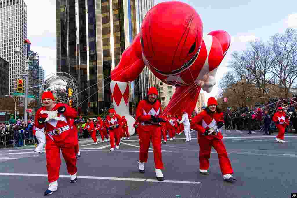 Los voluntarios del desfile luchan con los vientos mientras el globo del Power Rangers Mighty Morphin Red Ranger baja por Columbus Circle, en Nueva York.