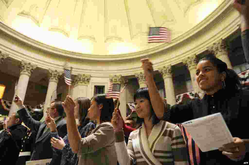 Candidates from 40 countries wave flags after they were naturalized as U.S. citizens in a ceremony at Federal Hall in New York. 