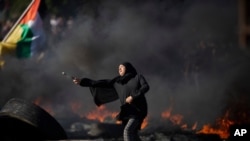 FILE - Palestinians clash with Israeli forces at the Hawara checkpoint, south of the West Bank city of Nablus, May 18, 2021.