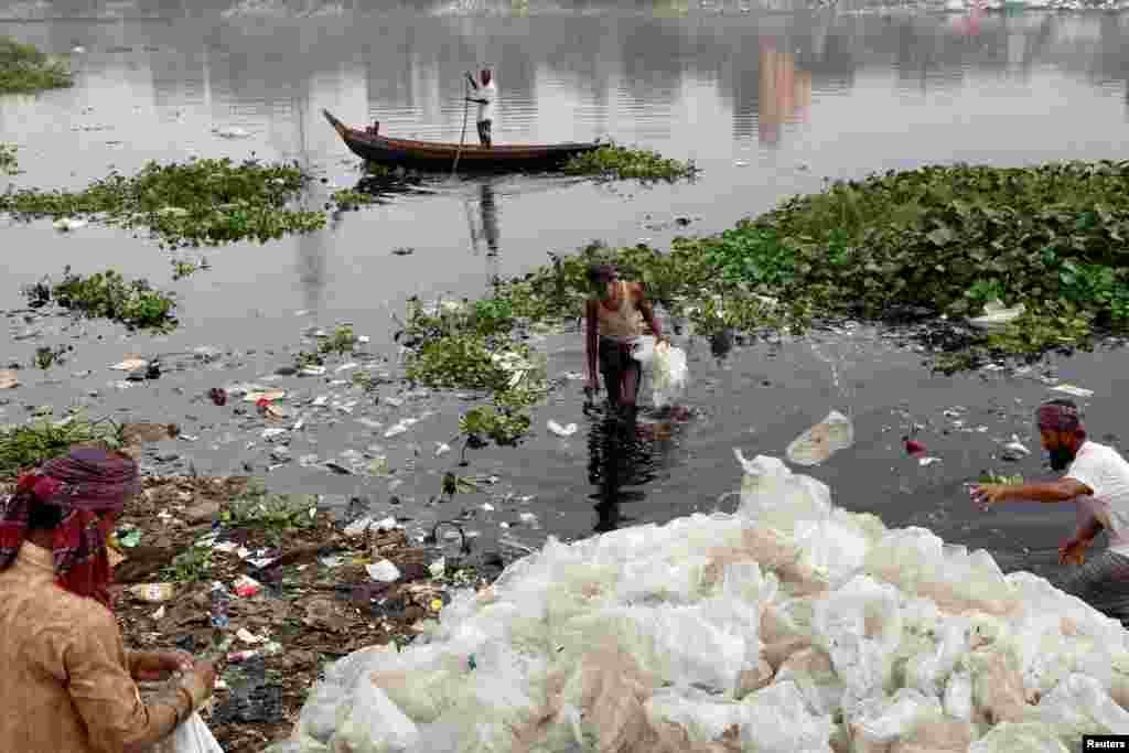 Men wash off plastic waste in the waters of the Buriganga River before they recycle it, in Dhaka, Bangladesh.