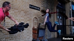 A woman poses for a photograph with the Harry Potter trolley at Kings Cross Station, in London, Britain, June 26, 2017. 