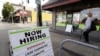 In this photo taken Thursday, June 4, 2020, a pedestrian wearing a mask walks past reader board advertising a job opening for a remodeling company, in Seattle. 