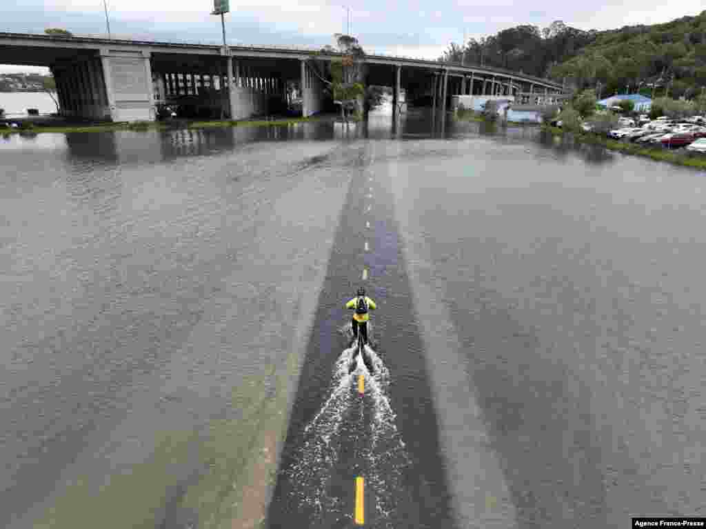 A man rides his bicycle along a flooded section of the Sausalito/Mill Valley bike path during the &quot;King Tide&quot; in Mill Valley, California, Jan. 3, 2022. &quot;King Tides&quot; occur when the Earth,the moon, and the sun align in orbit to produce unusually high water levels and can cause local tidal flooding.