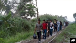 FILE - Migrants walk on train tracks on their journey from Central America to the U.S. border., in Palenque, Chiapas state, Mexico, Feb. 10, 2021. 